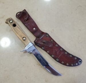 Knife with wooden handle and leather sheath.