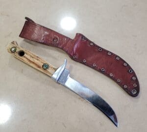 Knife with leather sheath on table.