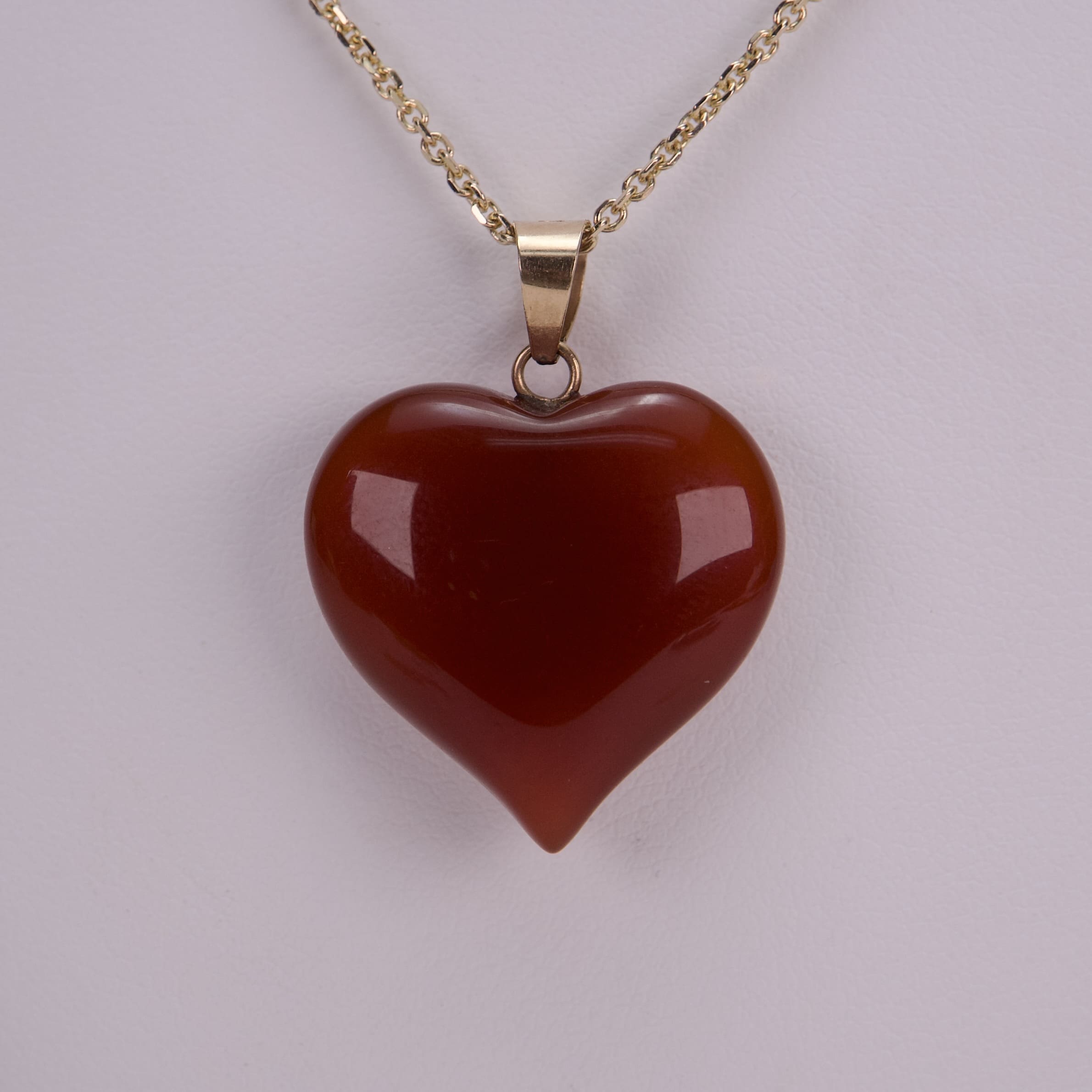 Red heart-shaped pendant on gold chain.