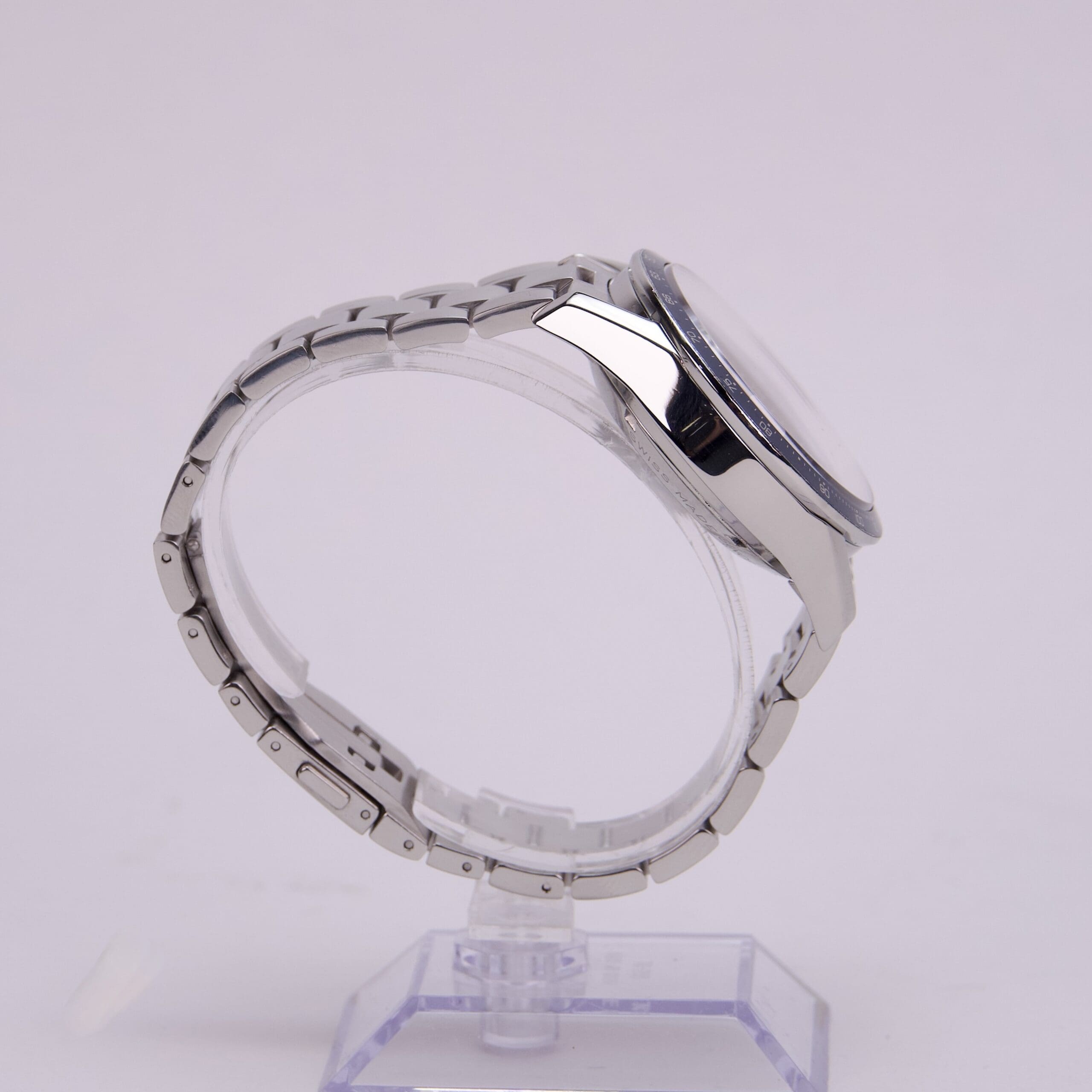Silver wristwatch on clear display stand.