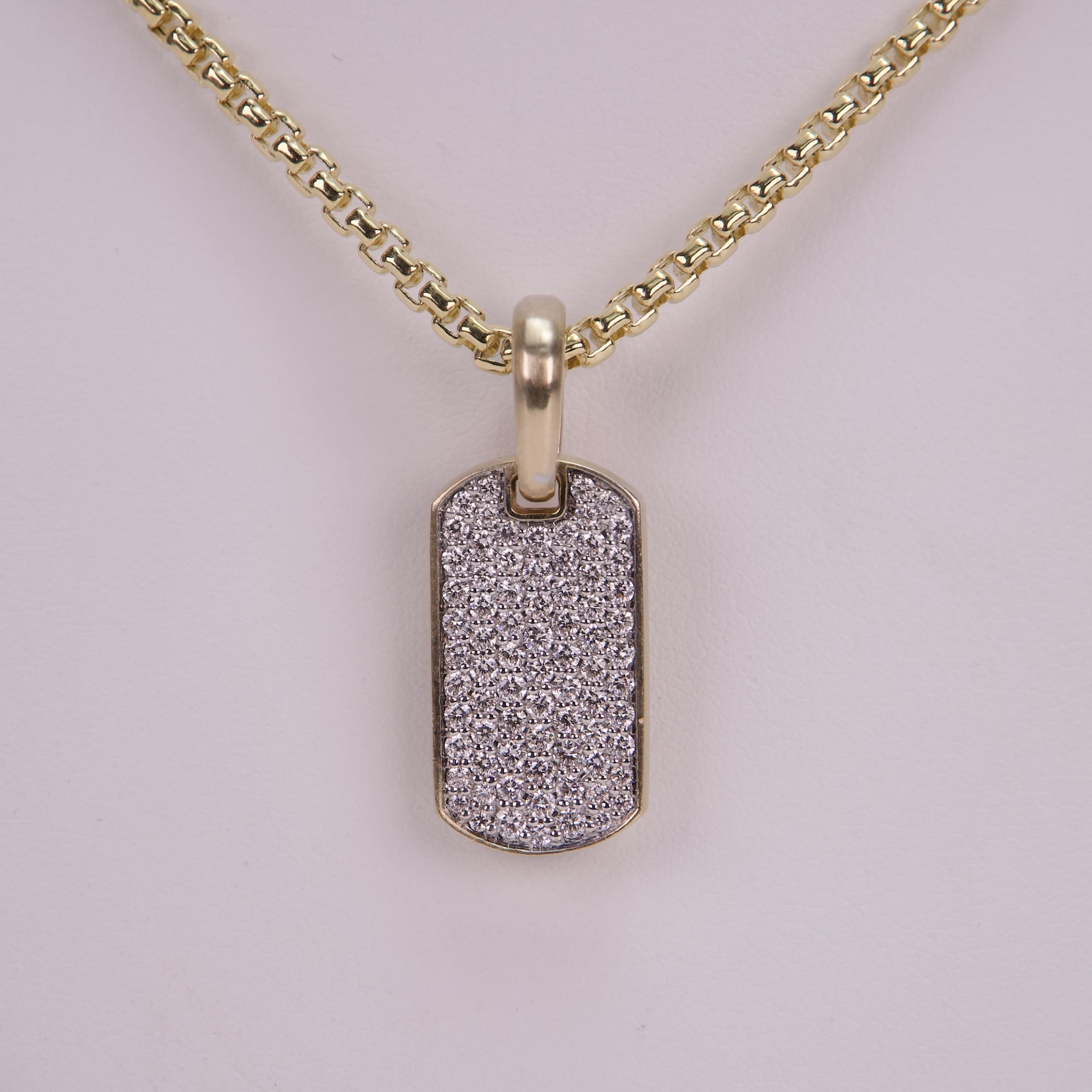 Gold chain with diamond-encrusted dog tag pendant.