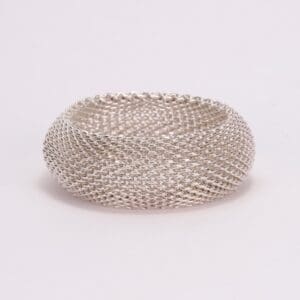 Silver mesh ring on plain background.