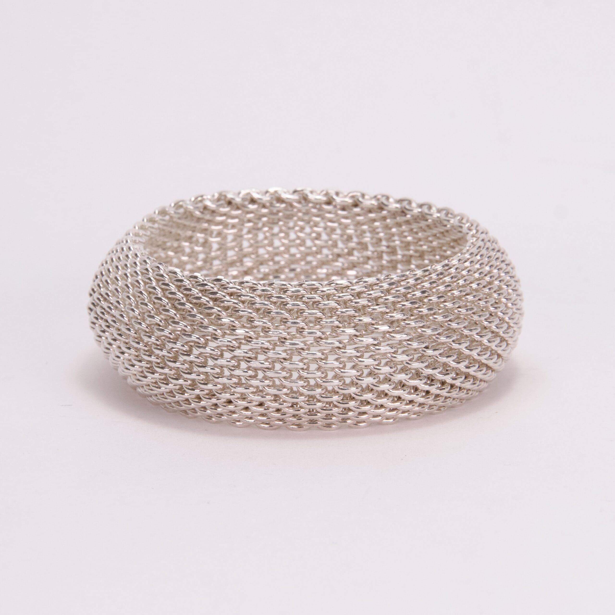 Silver mesh ring on plain background.