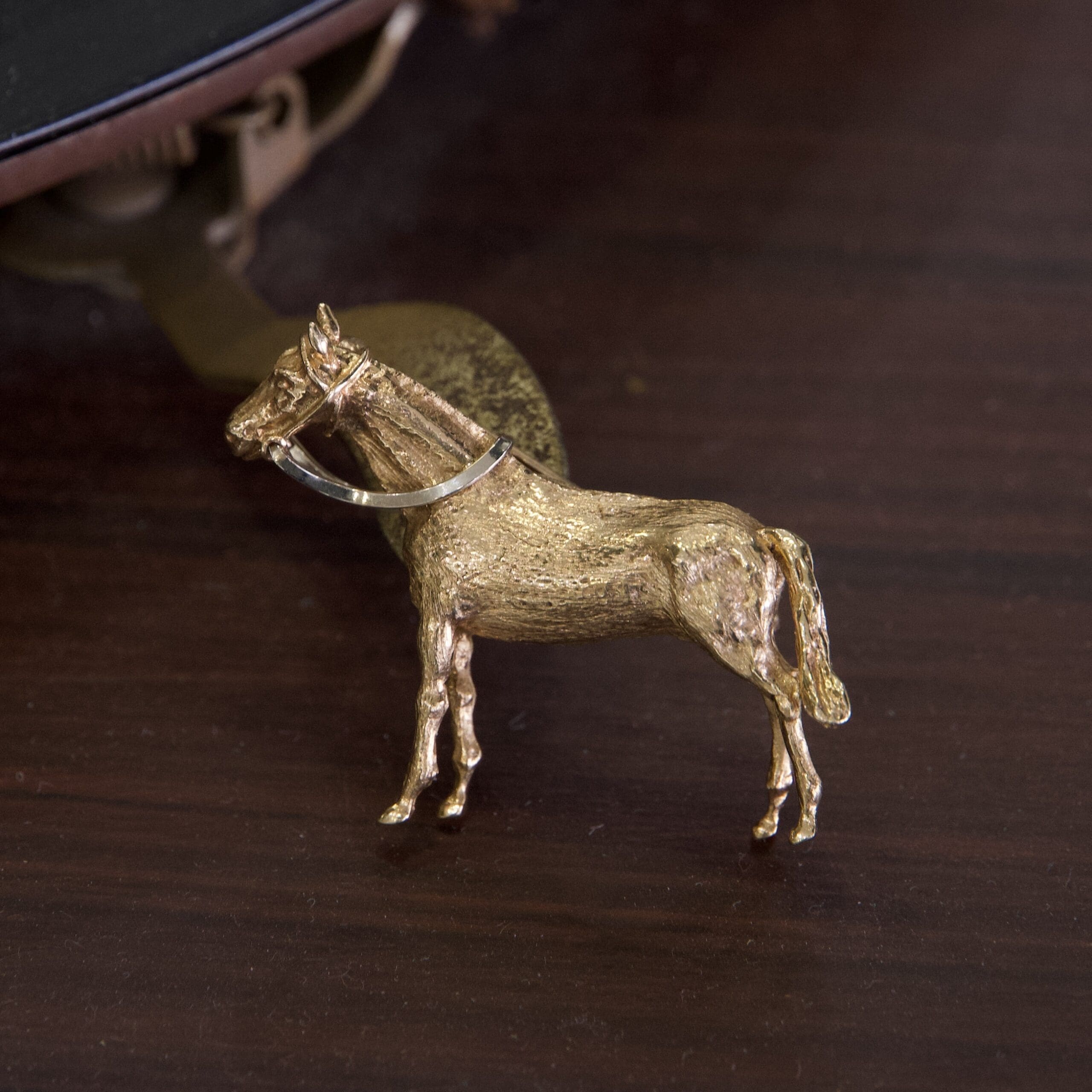 Golden horse figurine on wooden surface.