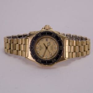 Gold wristwatch with black bezel, white dial.