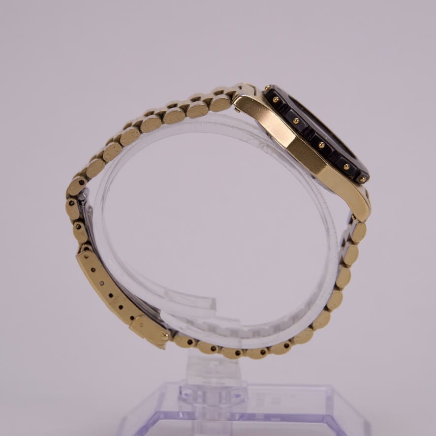 Gold wristwatch displayed on a clear stand.