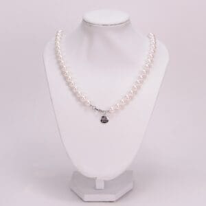 Pearl necklace on a white display stand.