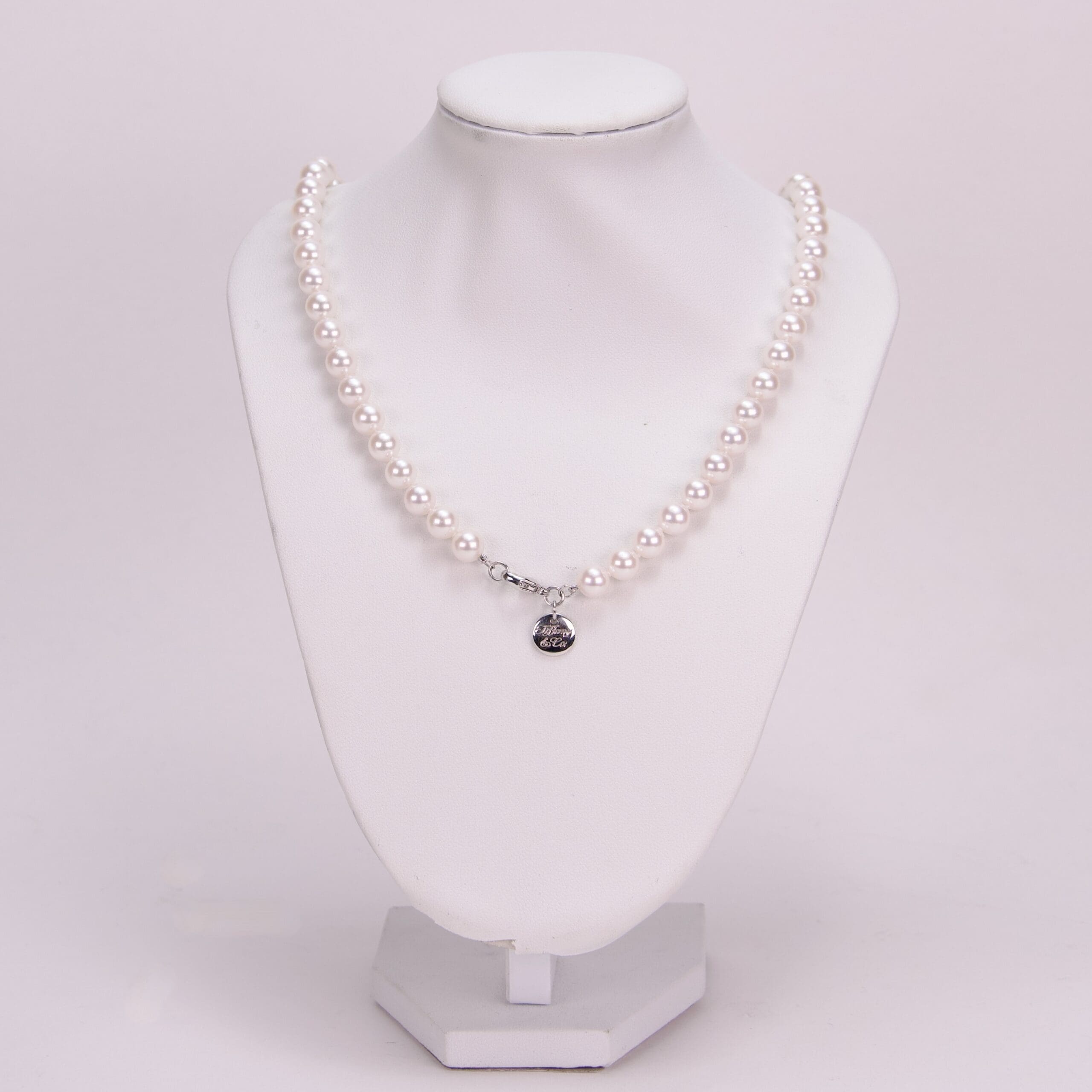 Pearl necklace on a white display stand.