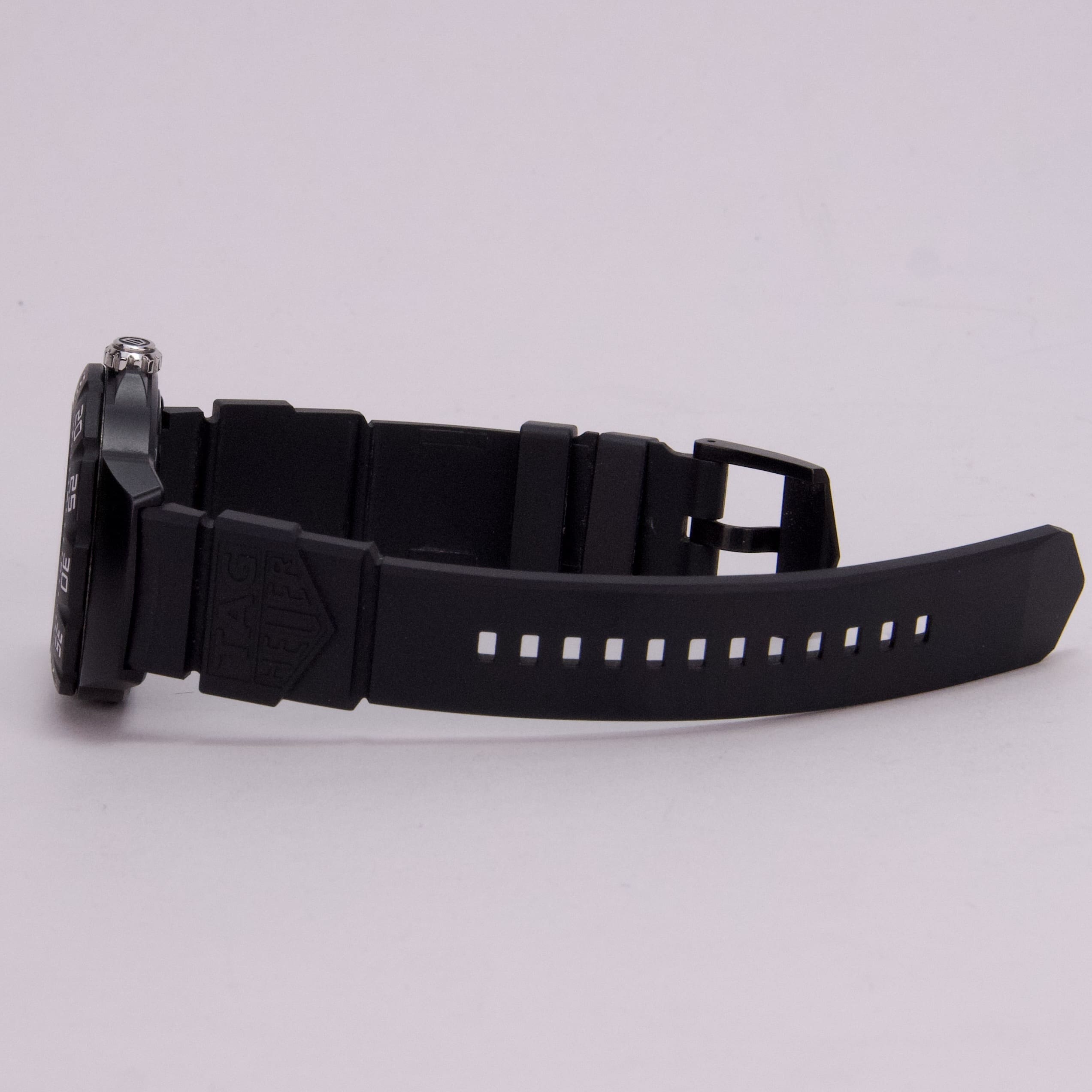 Black wristwatch with rubber strap, side view.