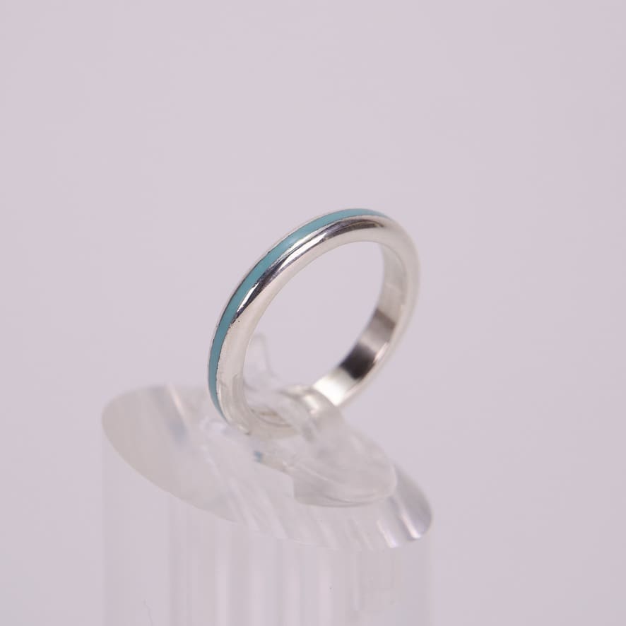 Silver ring with turquoise inlay on stand.