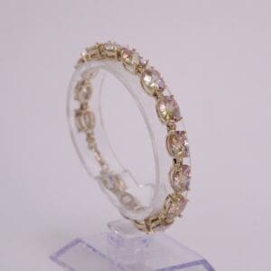 Gold bracelet with oval gemstones on stand.