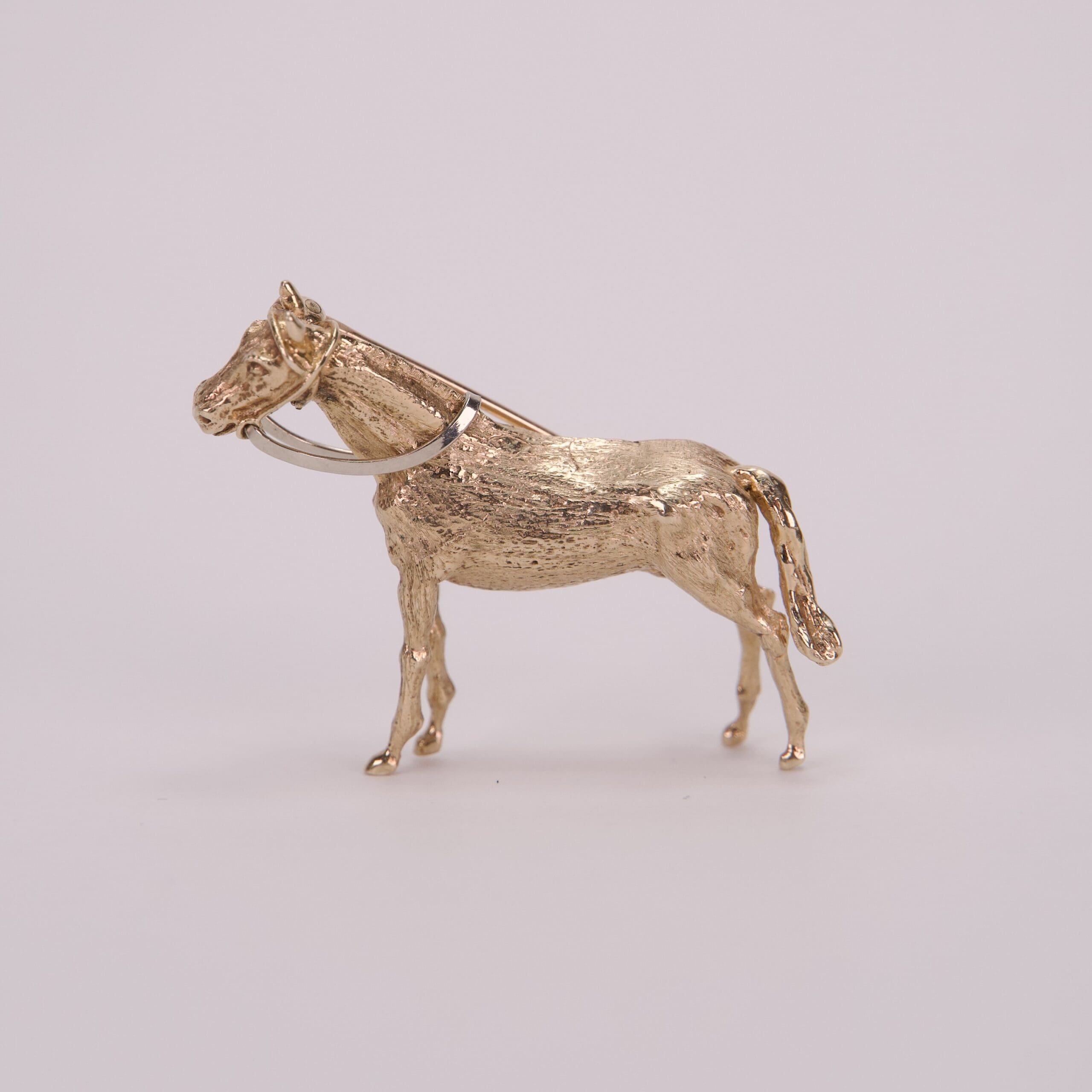 Gold horse figurine on a plain background.