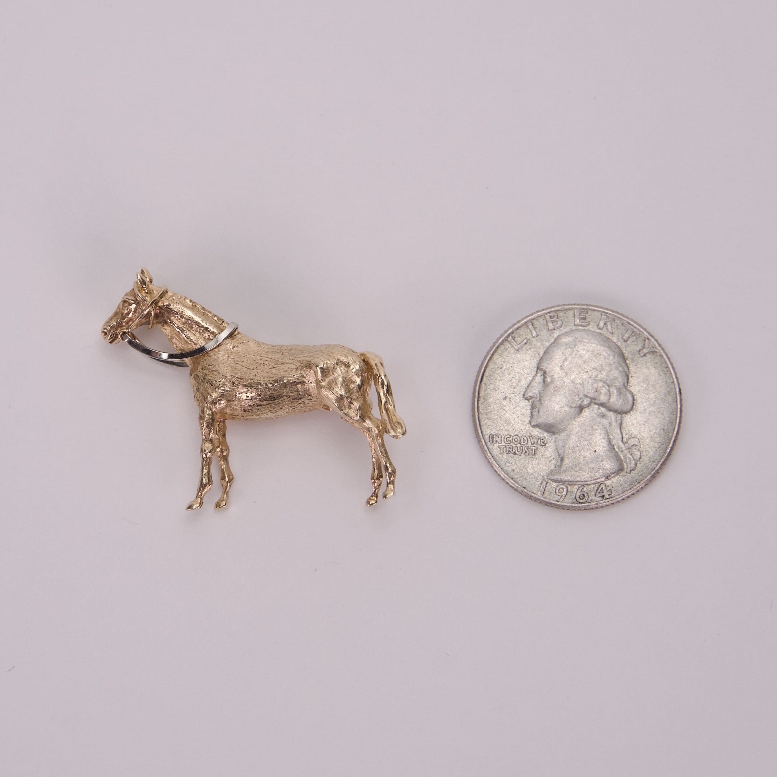 Gold donkey pin beside a quarter coin.