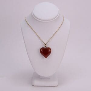 Gold necklace with red heart pendant.