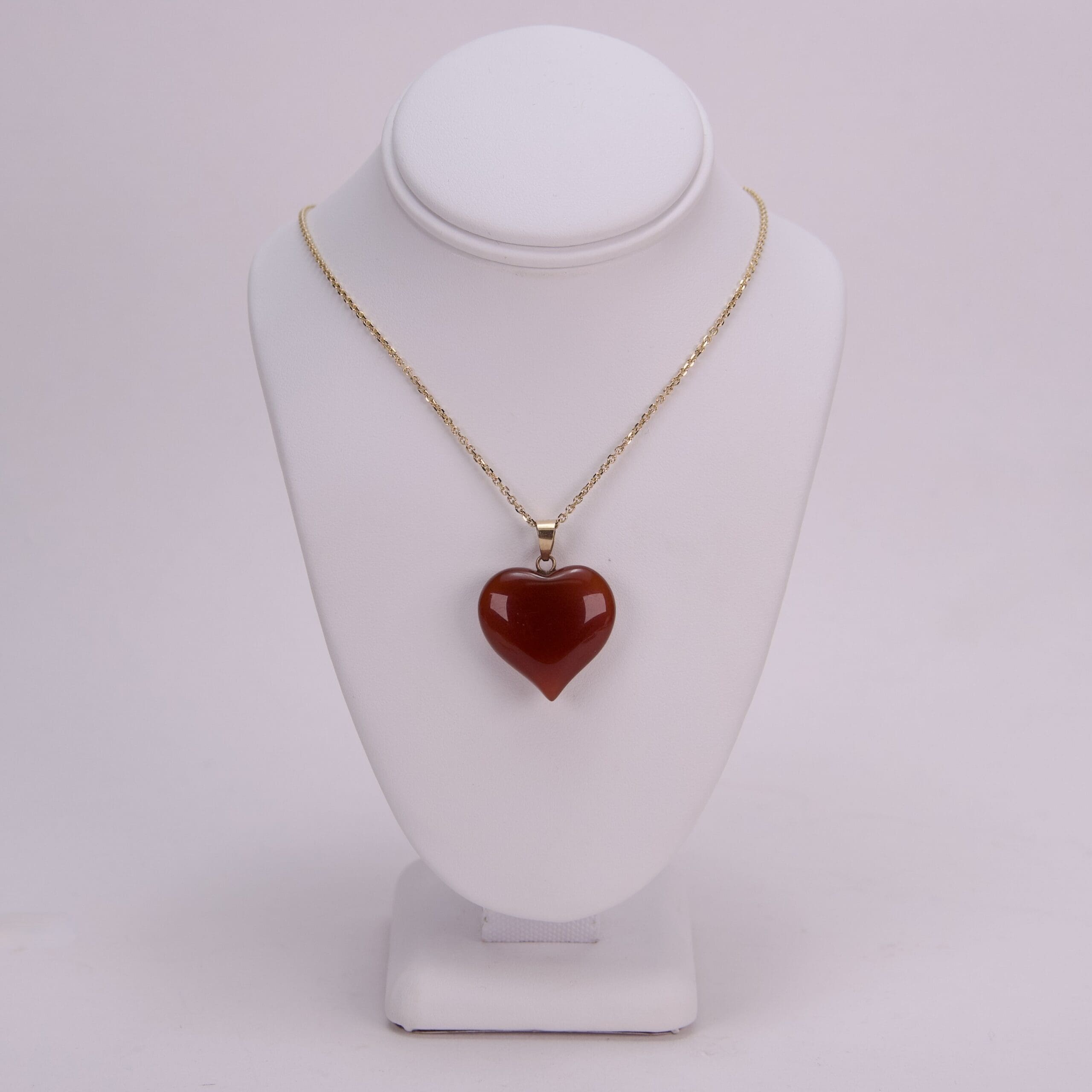 Gold necklace with red heart pendant.