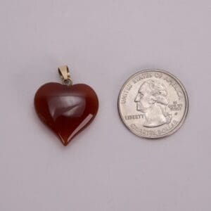 Heart-shaped pendant beside a quarter coin.