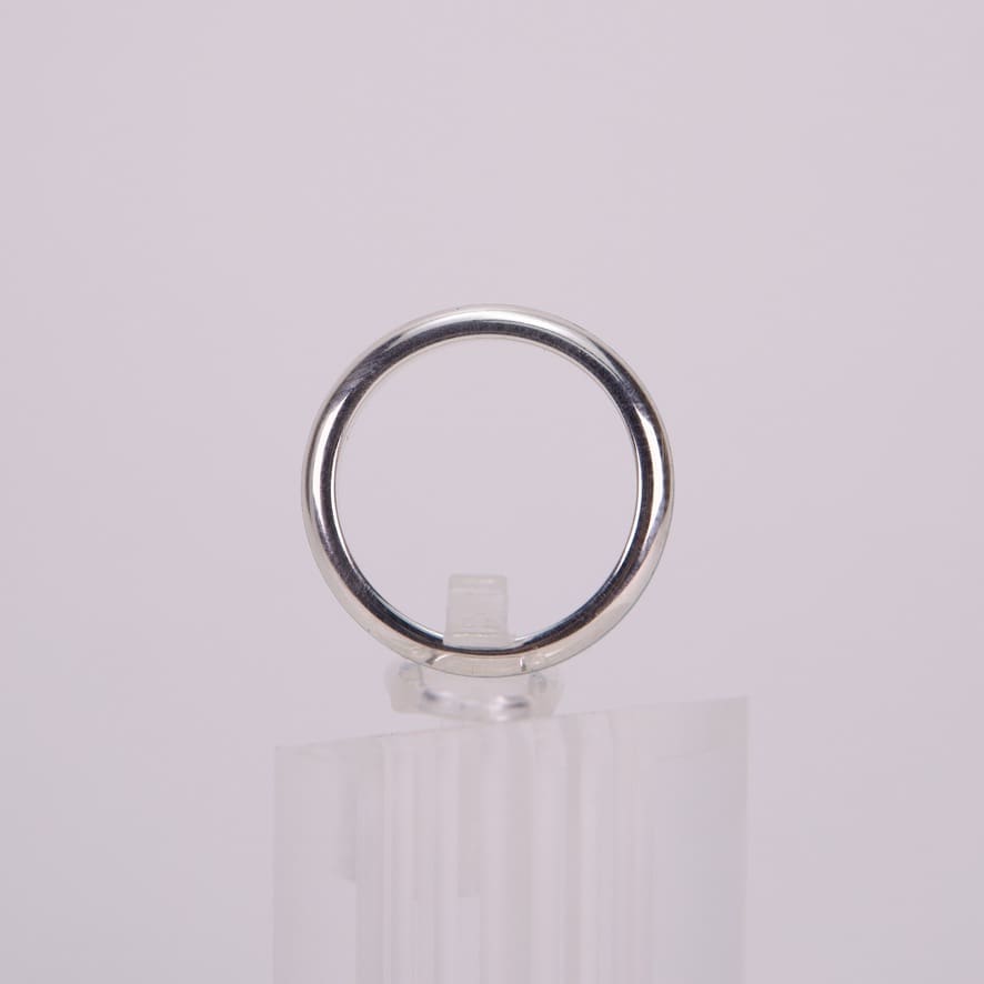 Silver ring displayed on a clear stand.