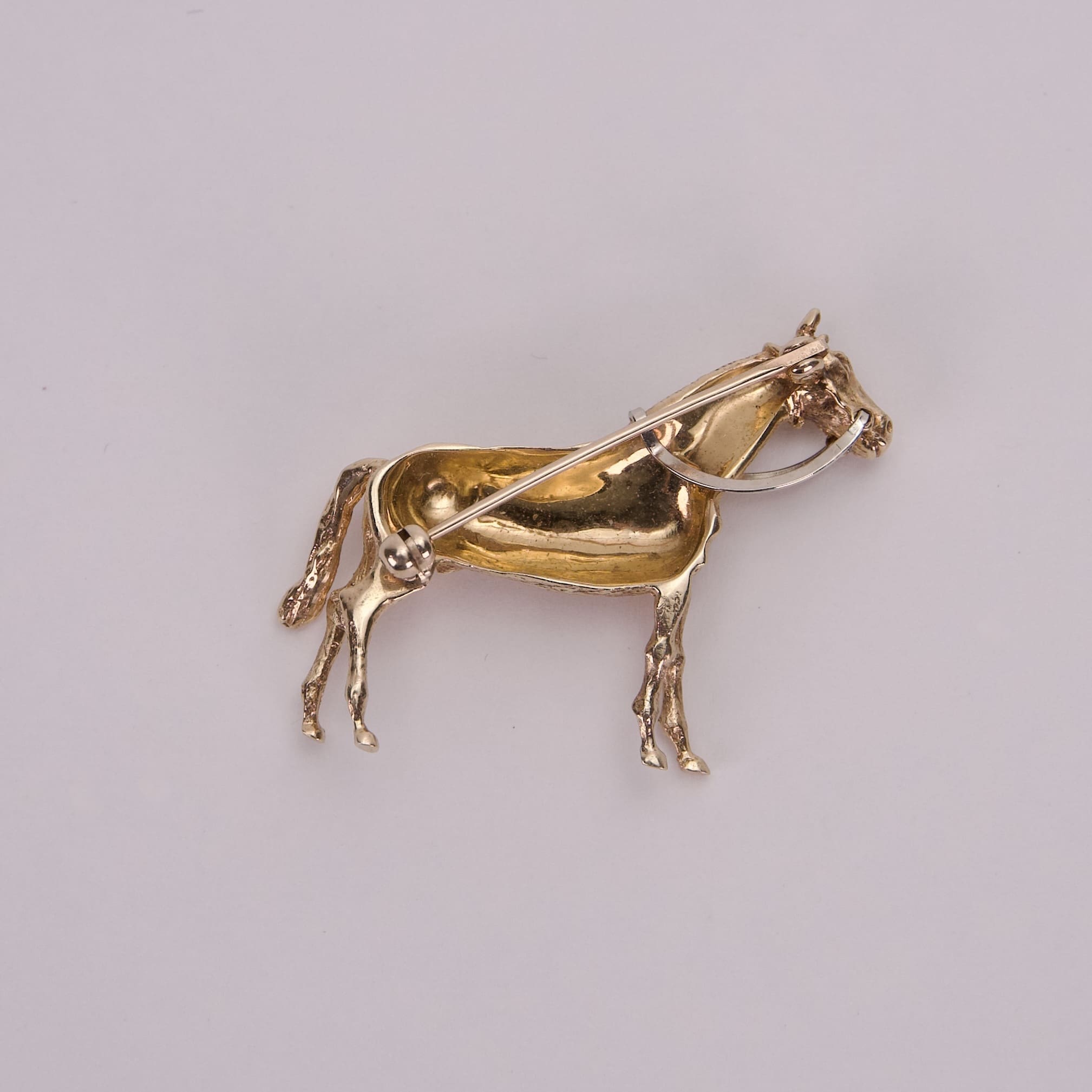 Gold horse-shaped brooch with intricate details.