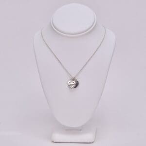 Heart pendant necklace on white display stand.