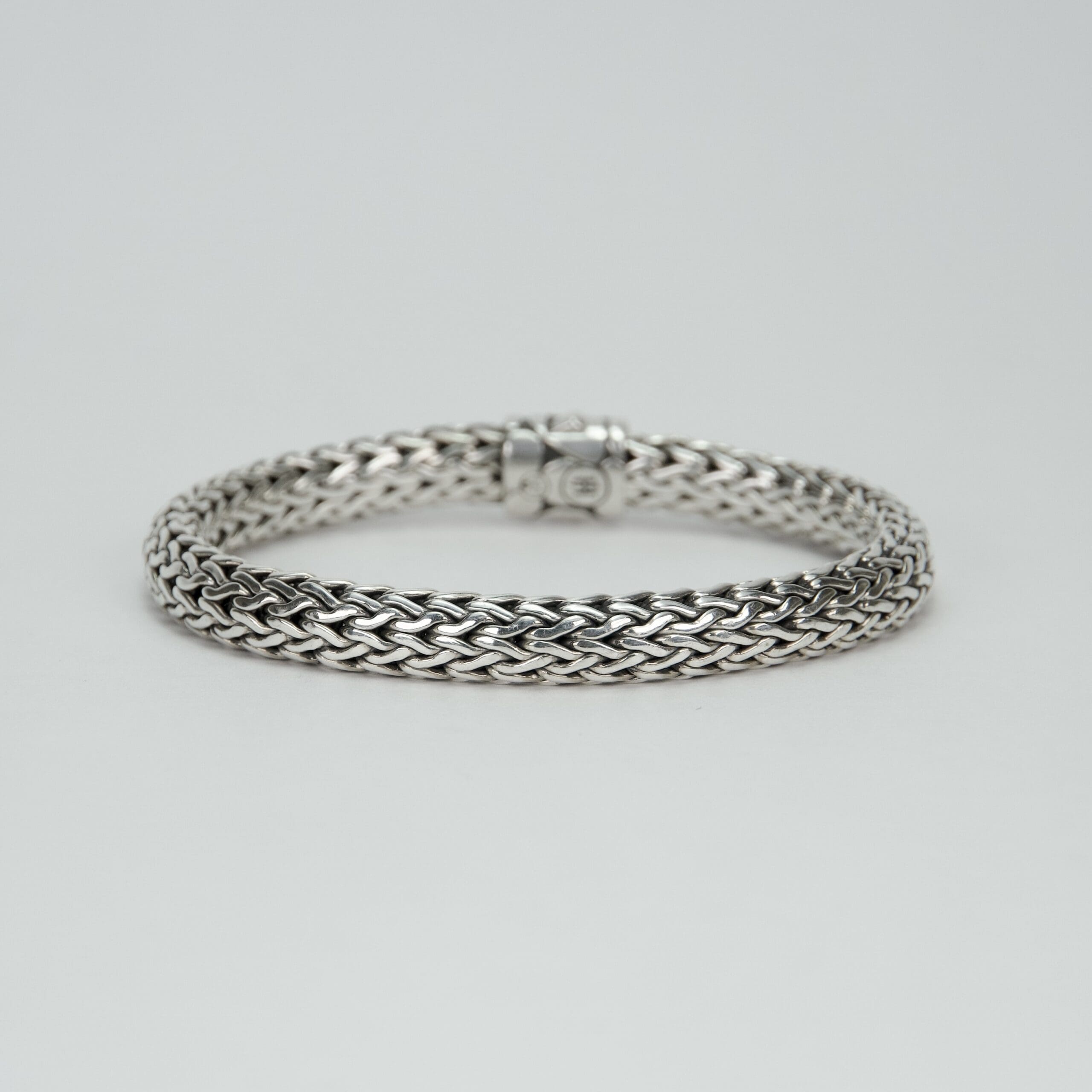 Silver braided bracelet on white background.