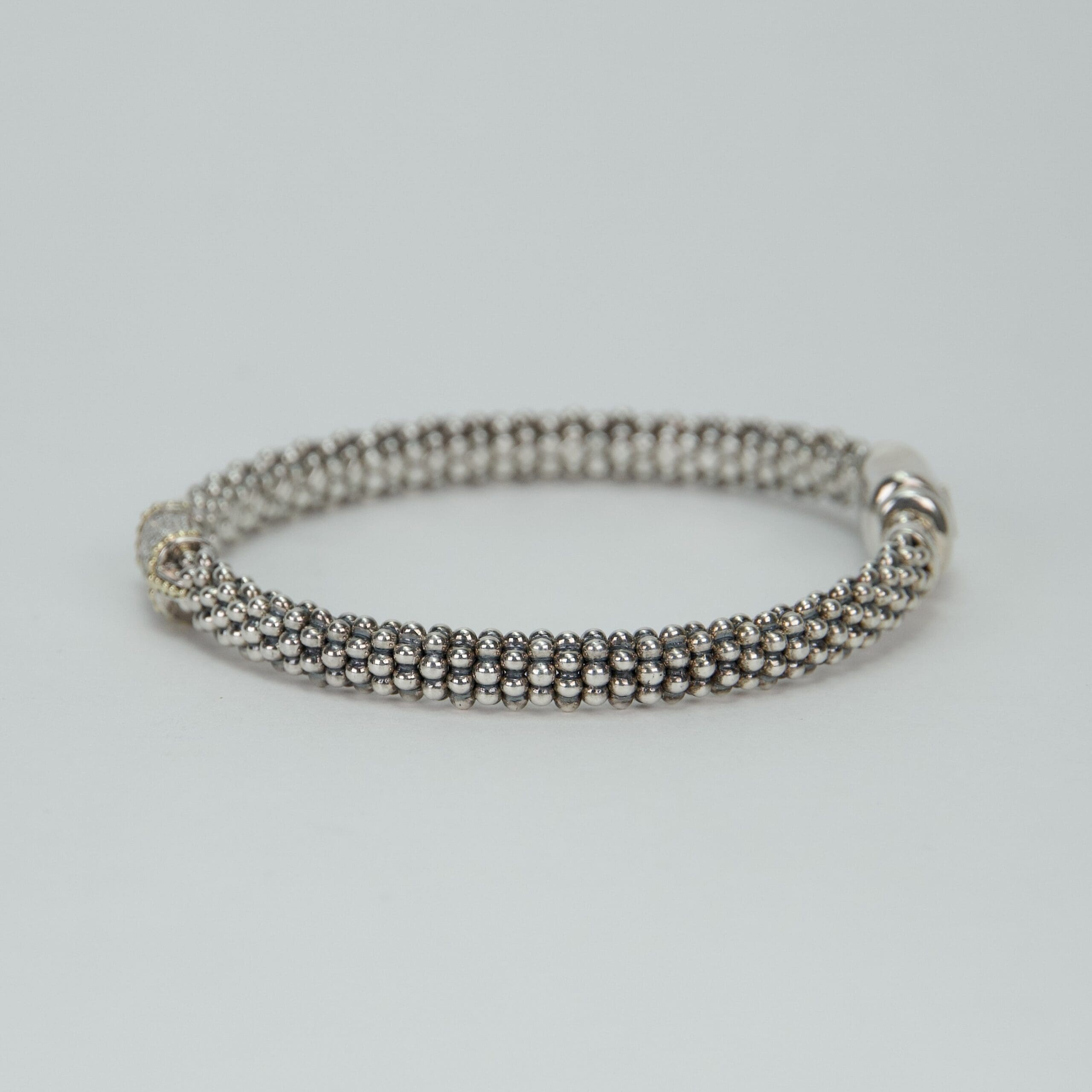 Silver beaded bracelet on plain background.