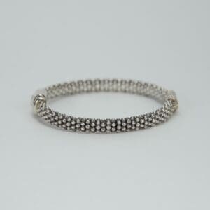 Silver bracelet with beaded design on display.