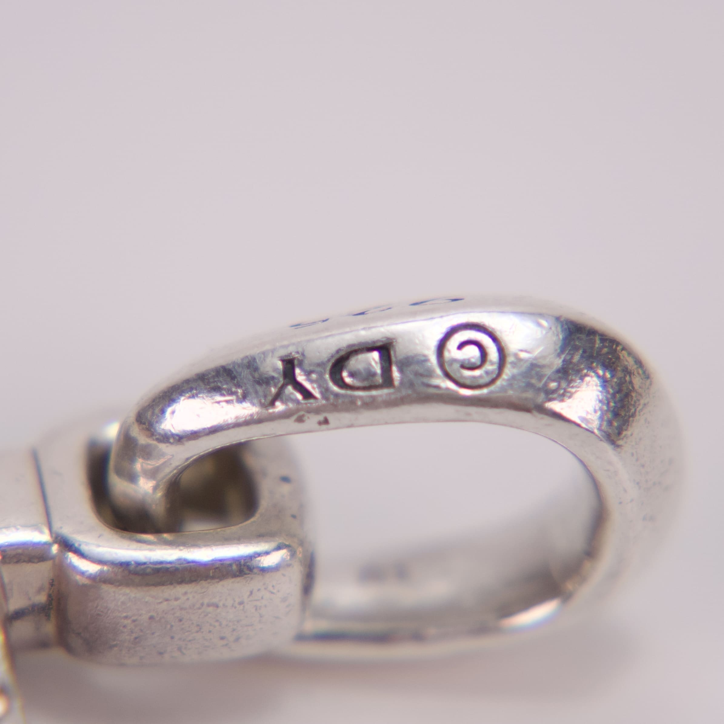 Close-up of silver clasp with engraving.