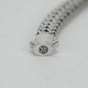 Silver bracelet clasp with engraved "M" logo.
