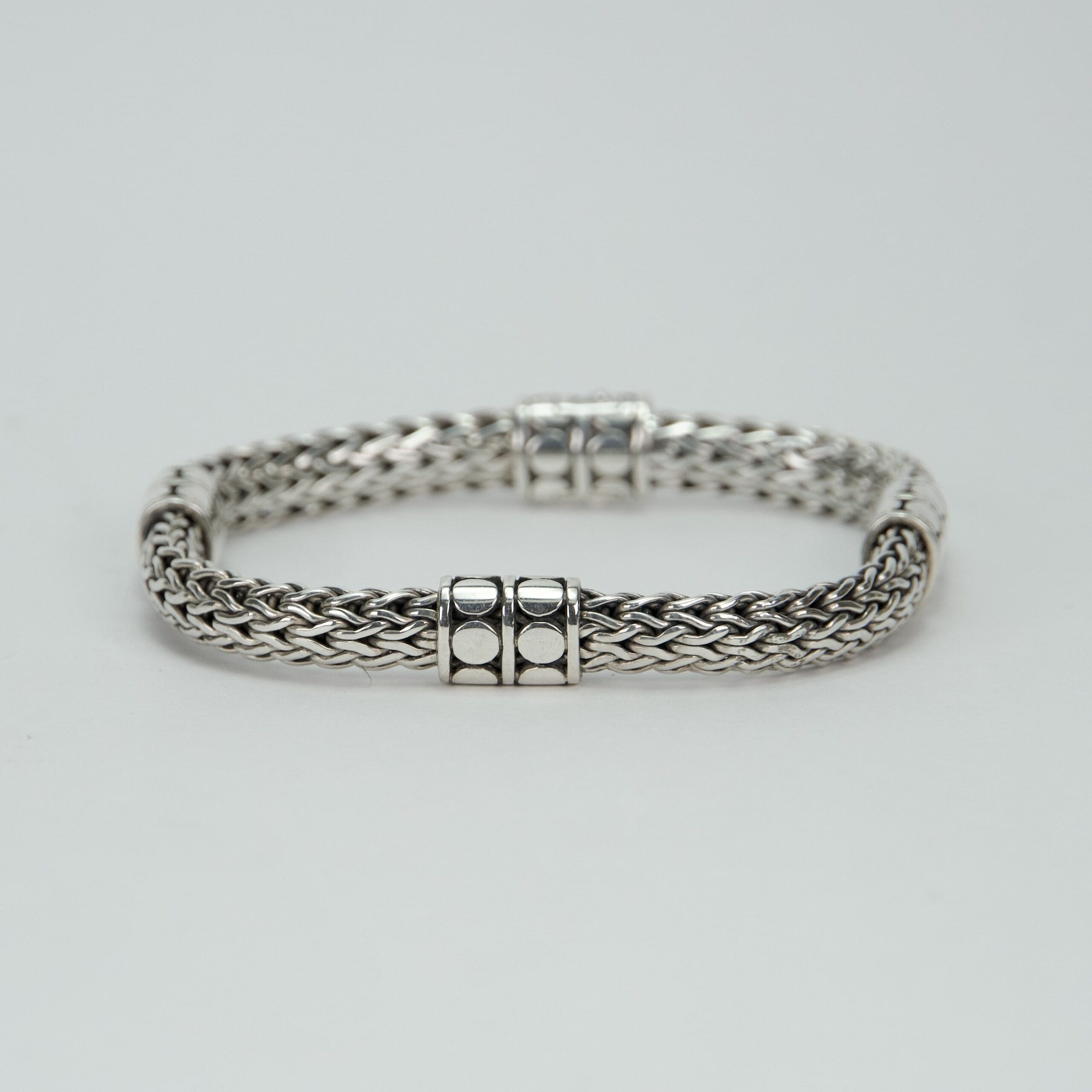 Silver woven bracelet with decorative clasps.