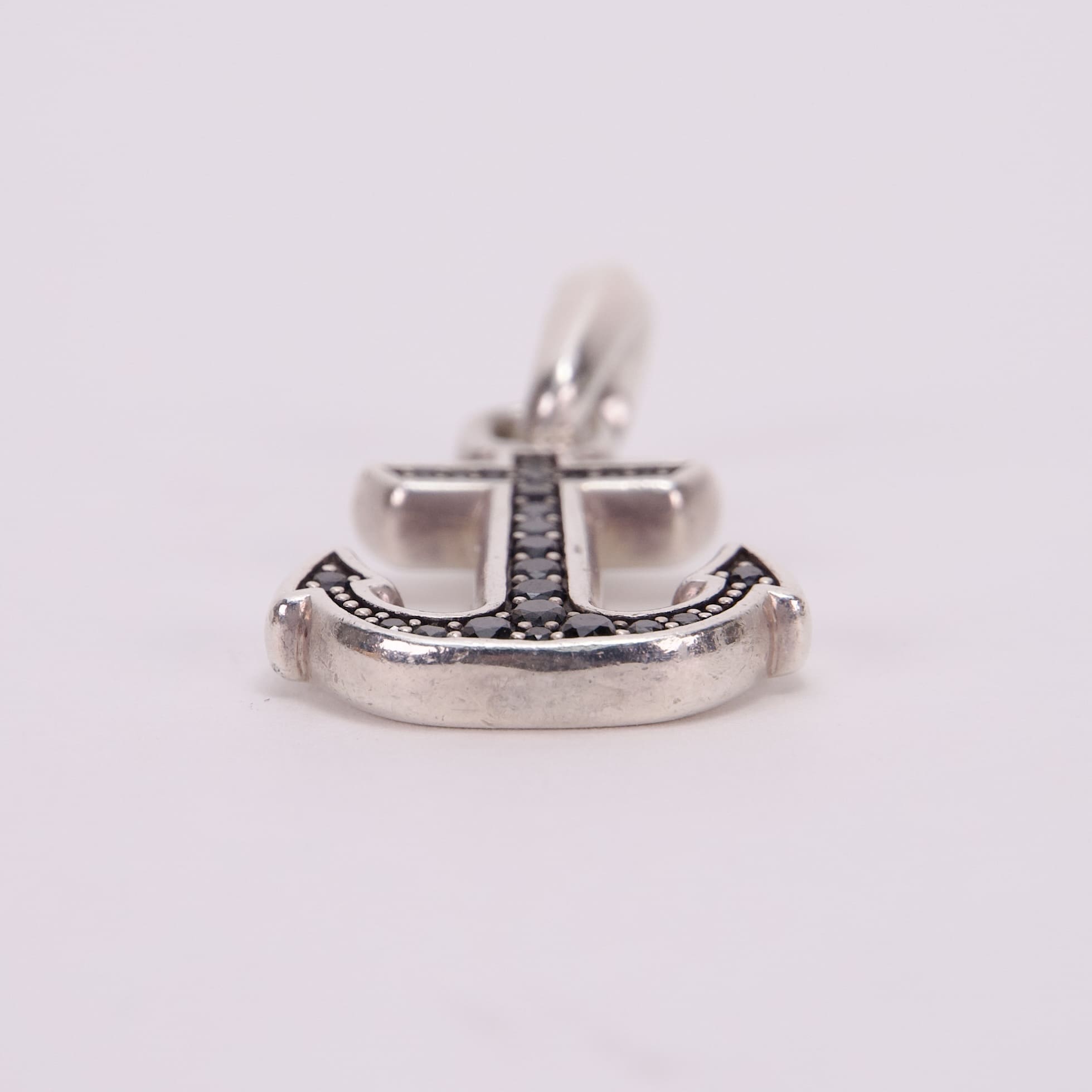 Anchor-shaped pendant with black gemstone accents.