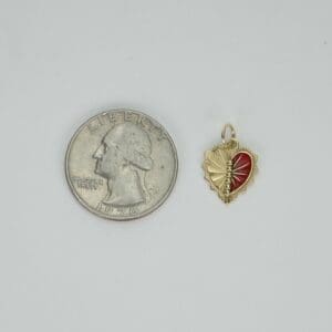 Red heart pendant beside a US quarter.