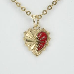 Gold heart pendant with red enamel design.