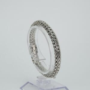 Silver woven bracelet on display stand.