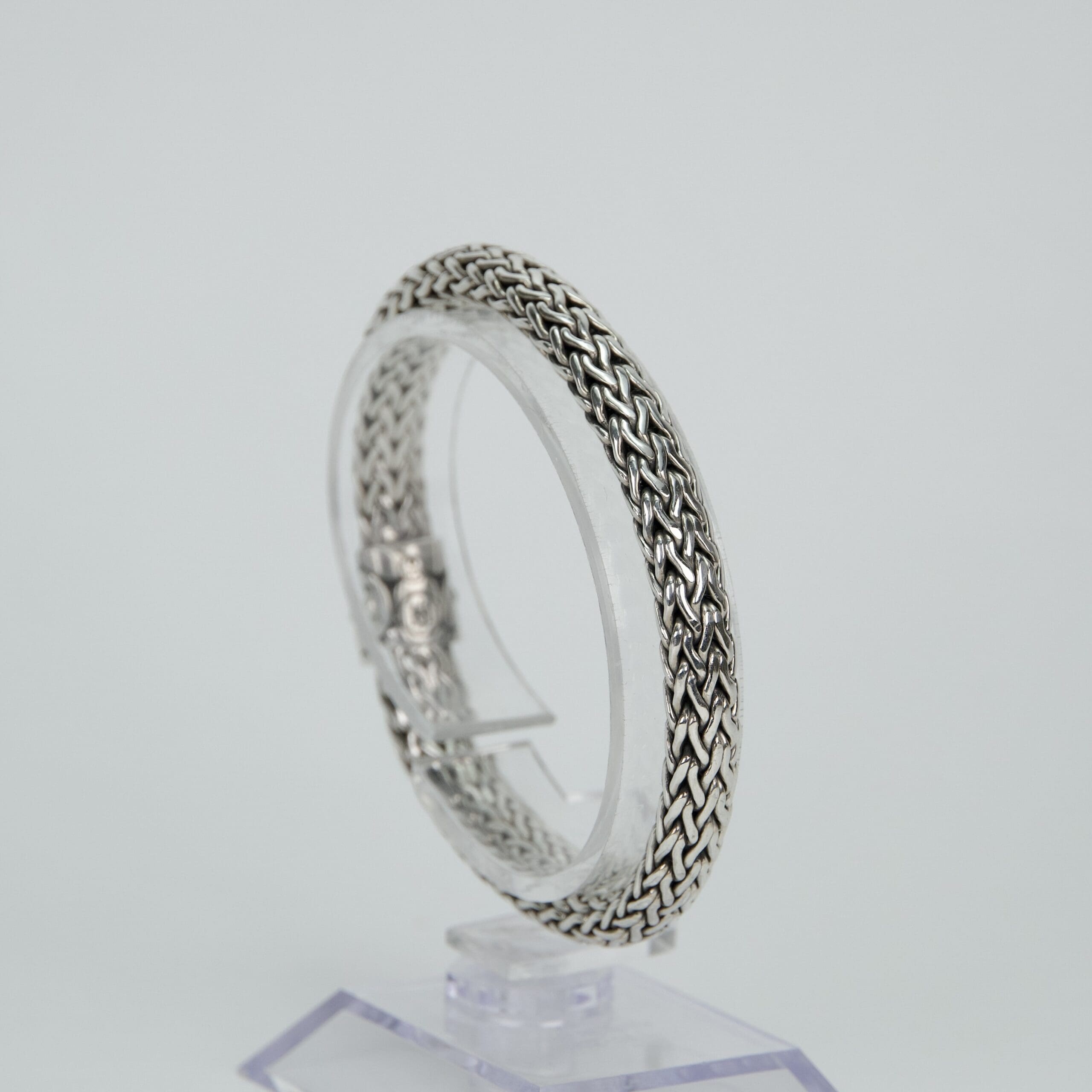 Silver woven bracelet on display stand.