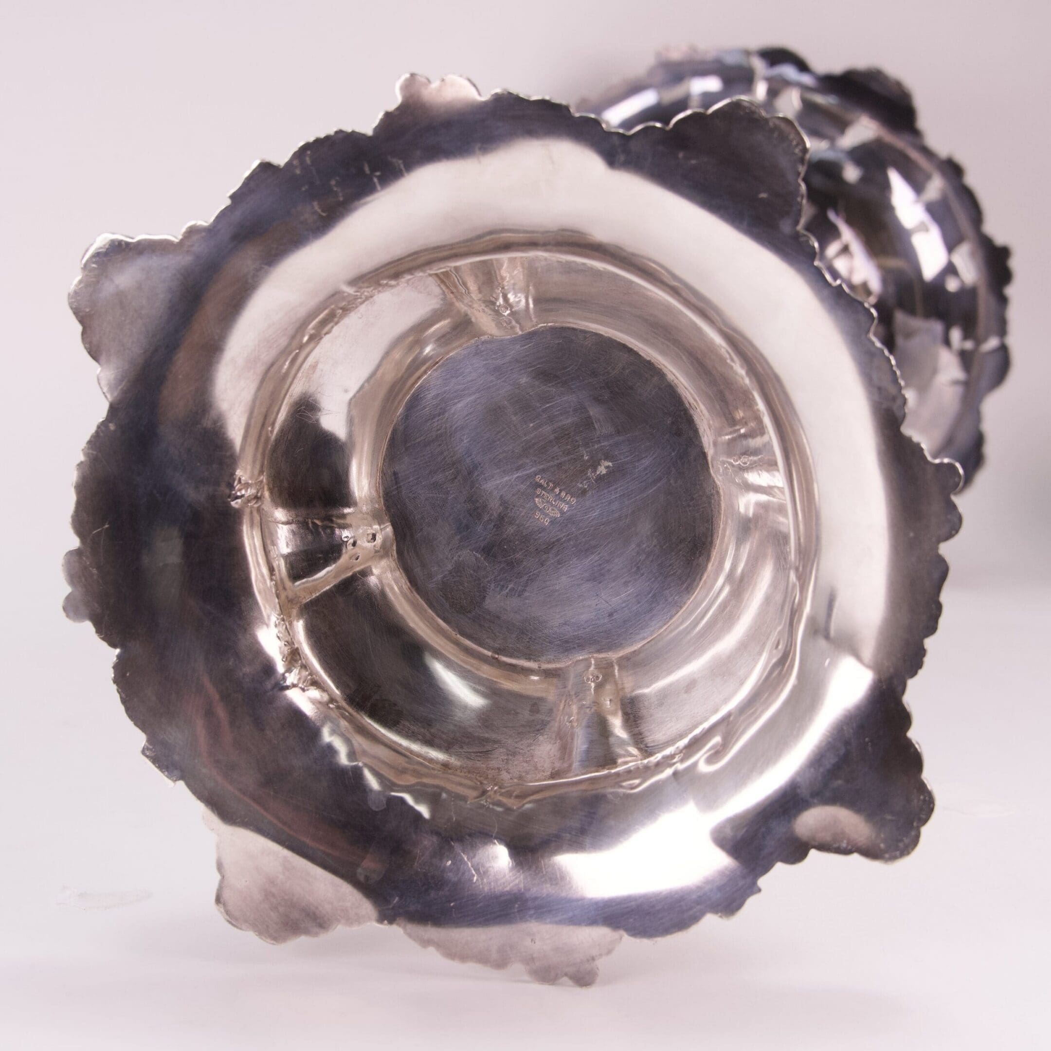 Bottom view of a silver ornate candleholder.