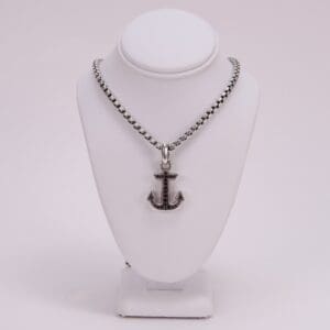 Anchor pendant necklace on display stand.