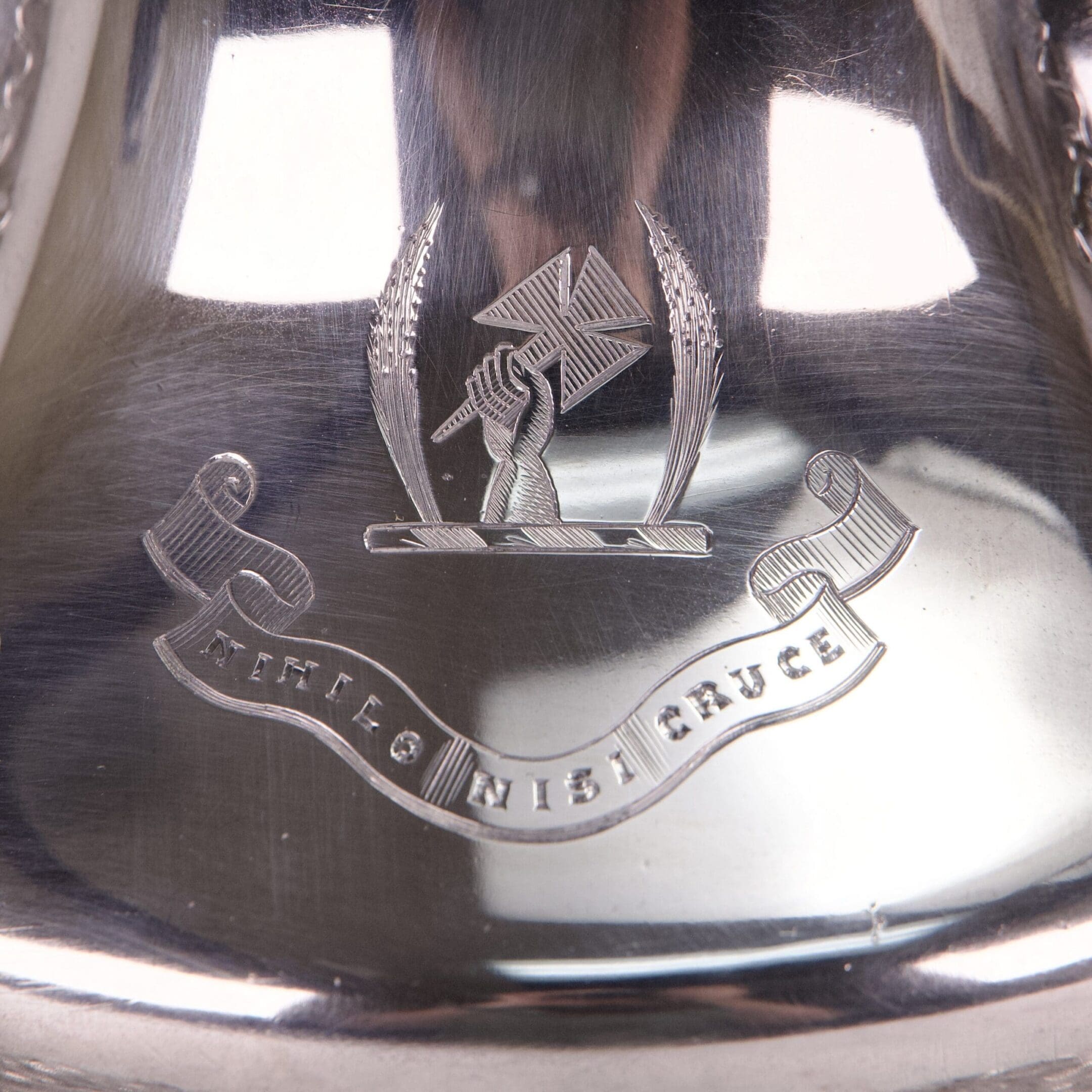 Engraved silver item with emblem and motto.