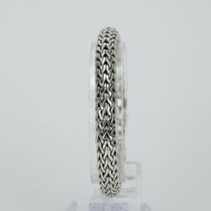 Silver chain bracelet on a clear stand.