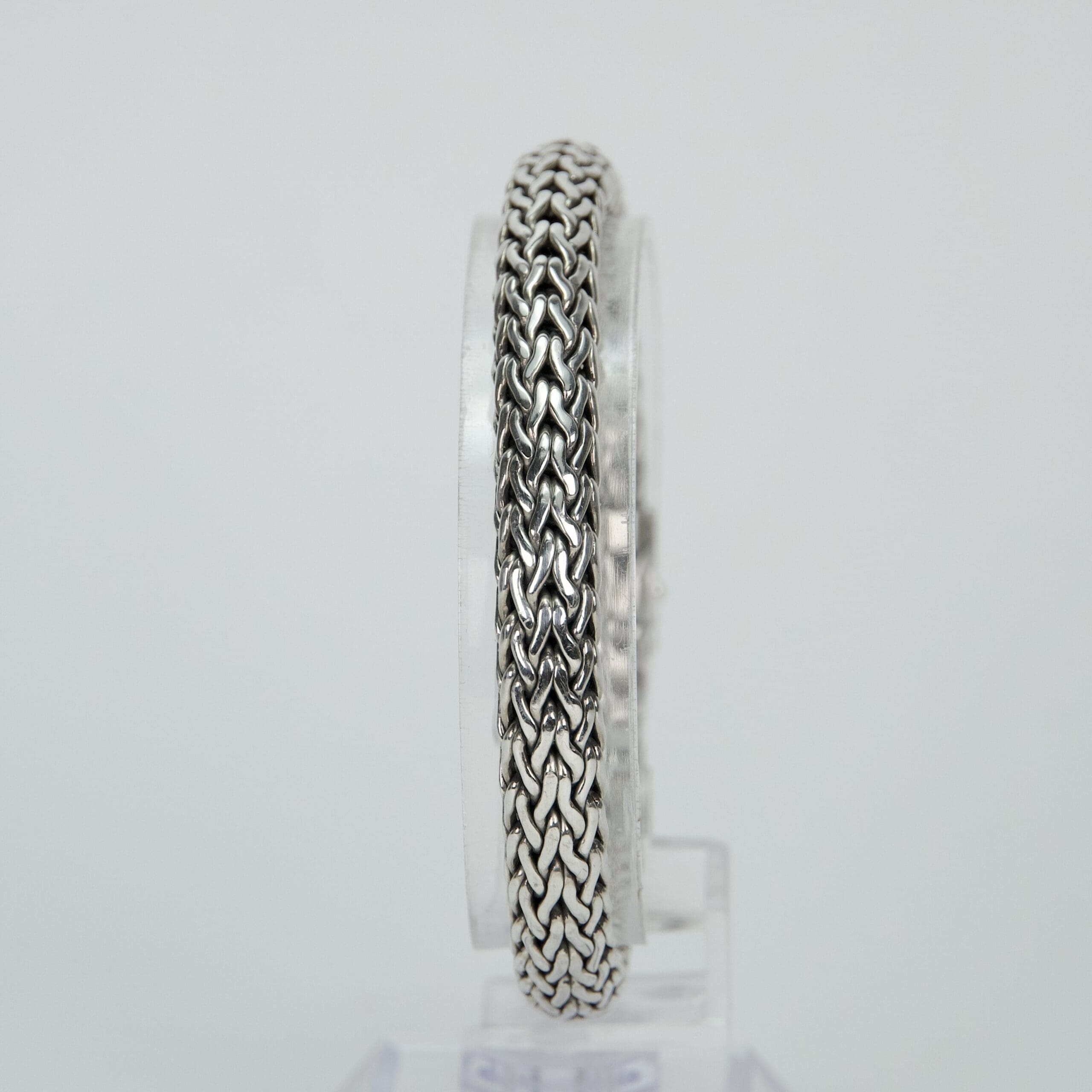 Silver chain bracelet on a clear stand.