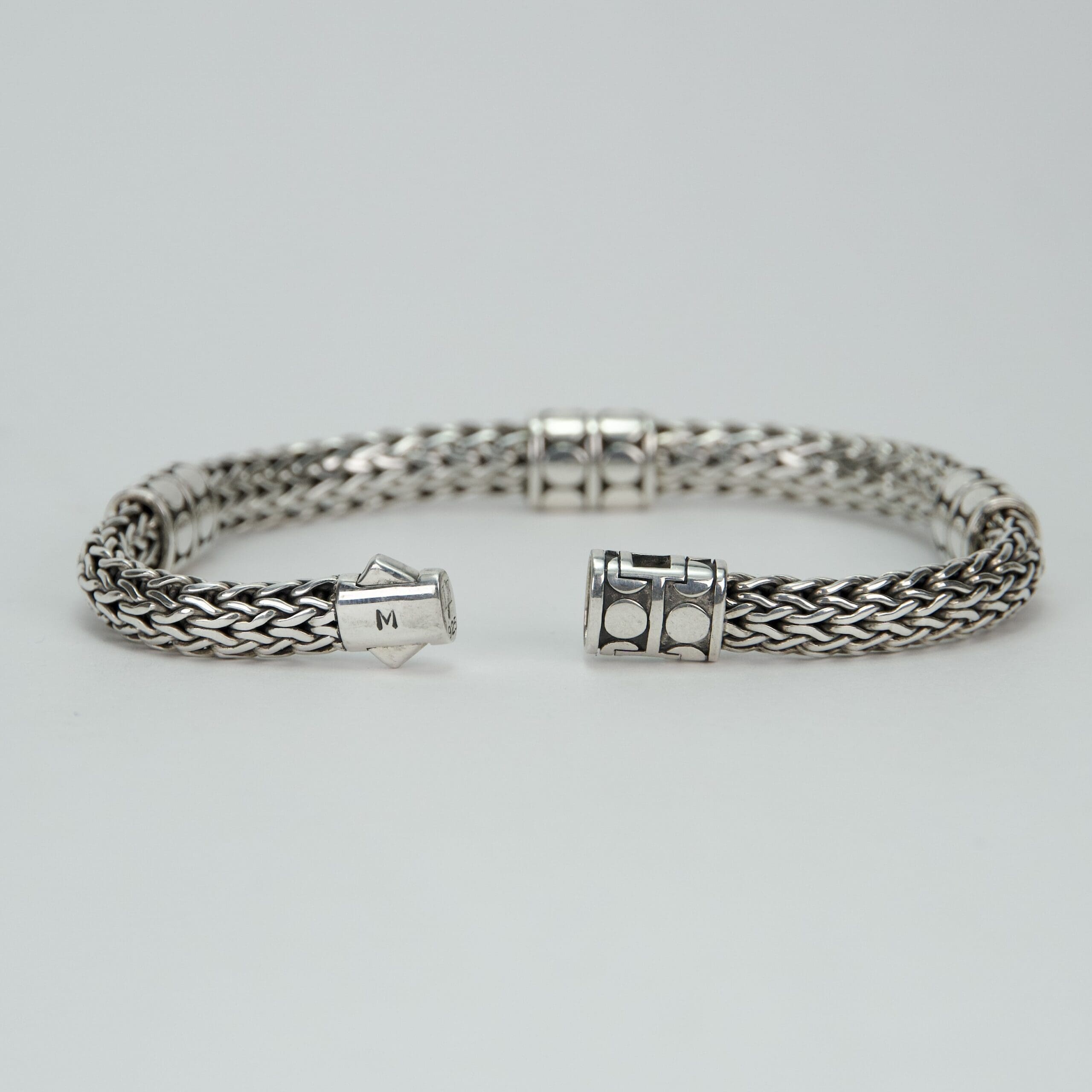 Silver woven bracelet with decorative clasps.