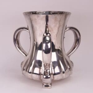Silver cup with two handles and spout.