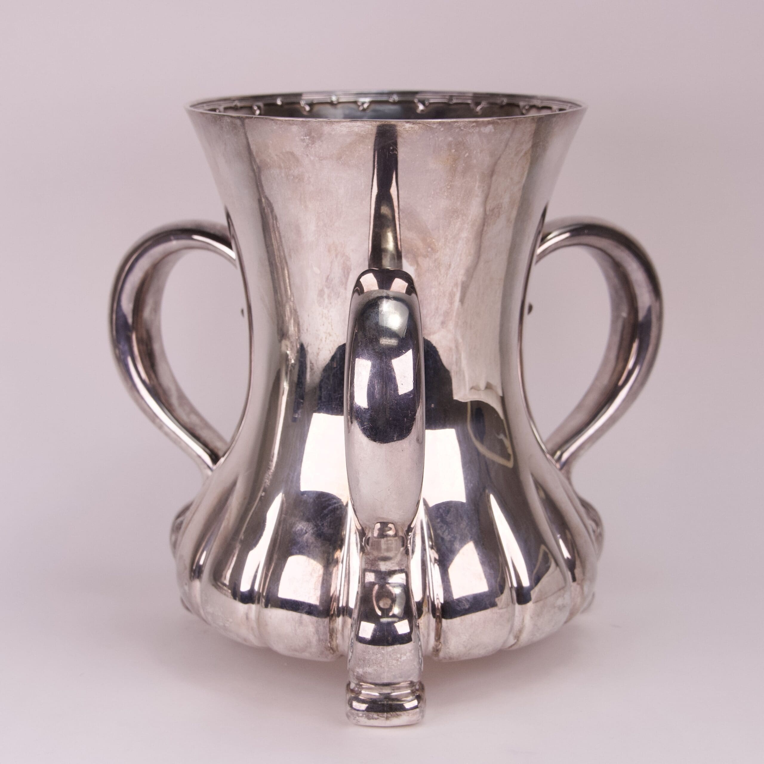 Silver cup with two handles and spout.