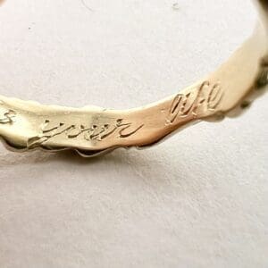 Engraved gold ring with cursive inscription.