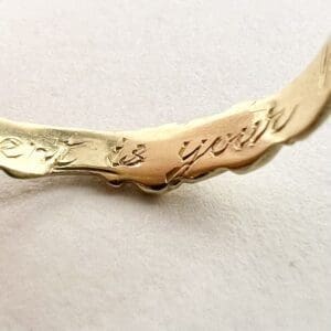 Gold bracelet with engraved text detail.