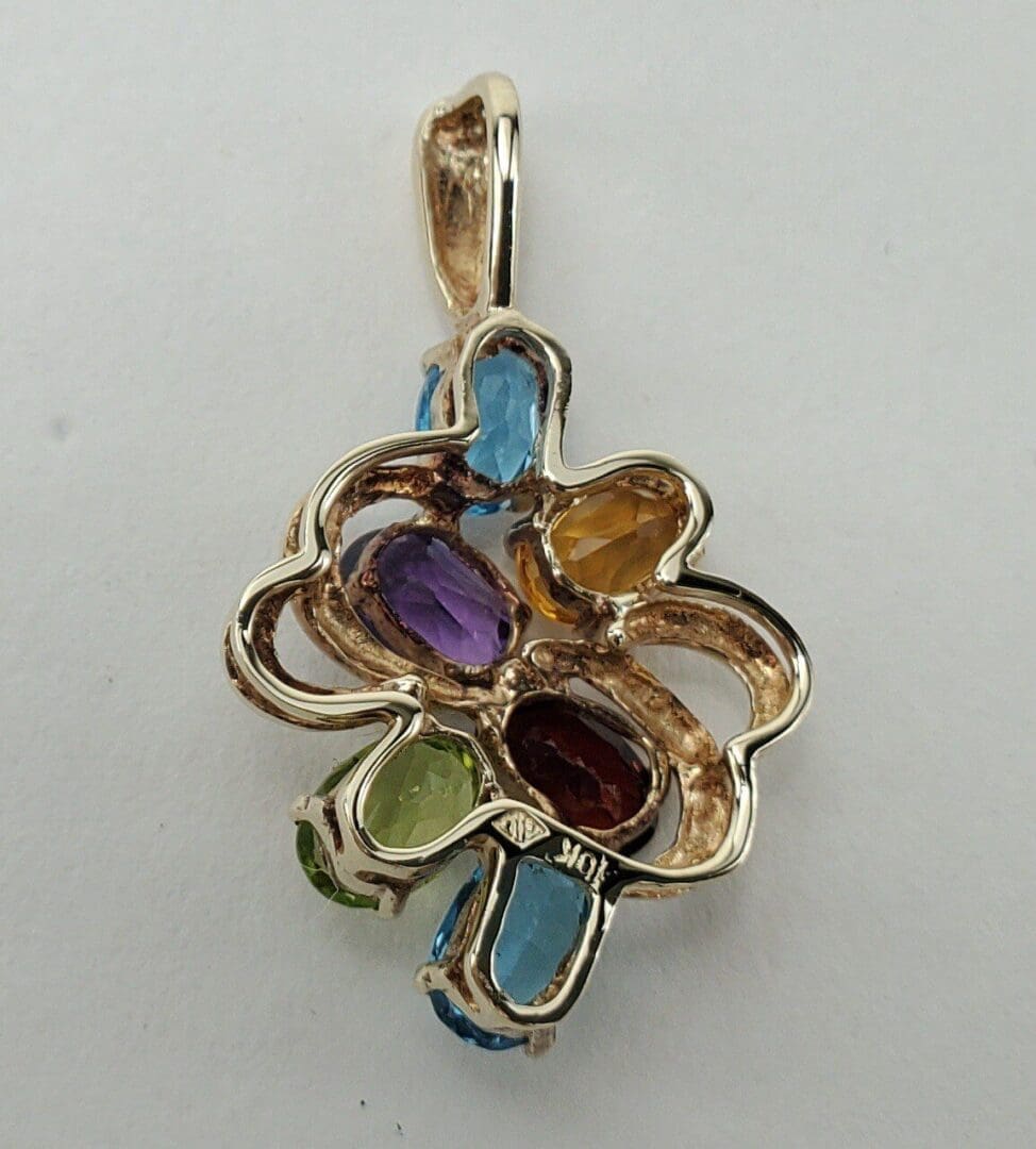Gold pendant with colorful gemstones, intricate design.