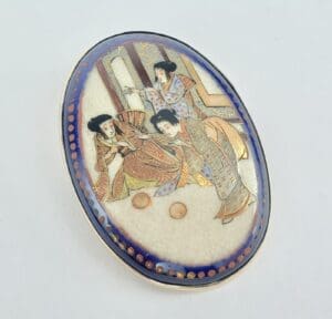 Decorative oval brooch with traditional Japanese design.