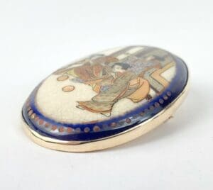Oval brooch with traditional Japanese artwork.