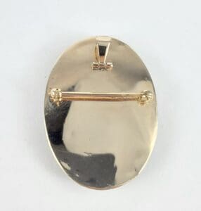 Gold oval pin with clasp on back.