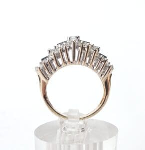 Gold ring with diamonds on clear stand.