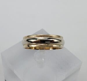 Gold wedding band on display stand.